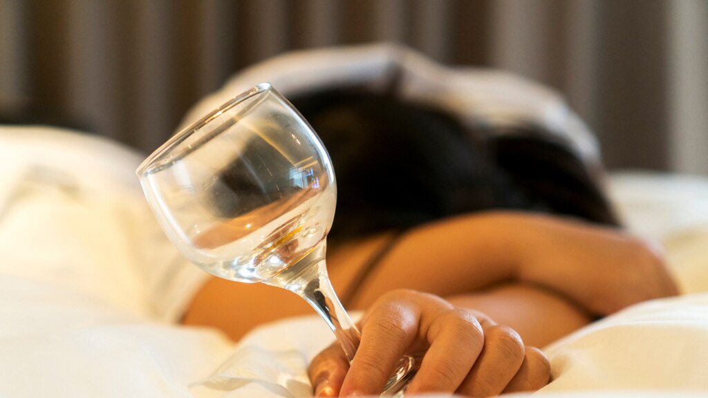A woman relaxing in bed with a glass of wine.