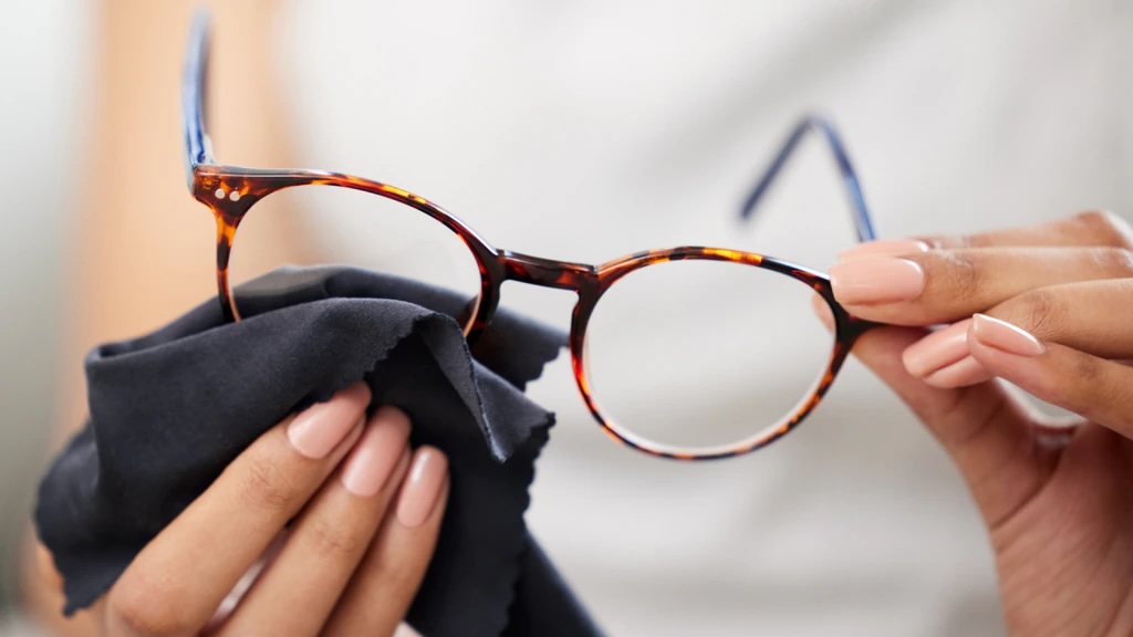 A woman holding a pair of glasses, looking stylish and sophisticated.