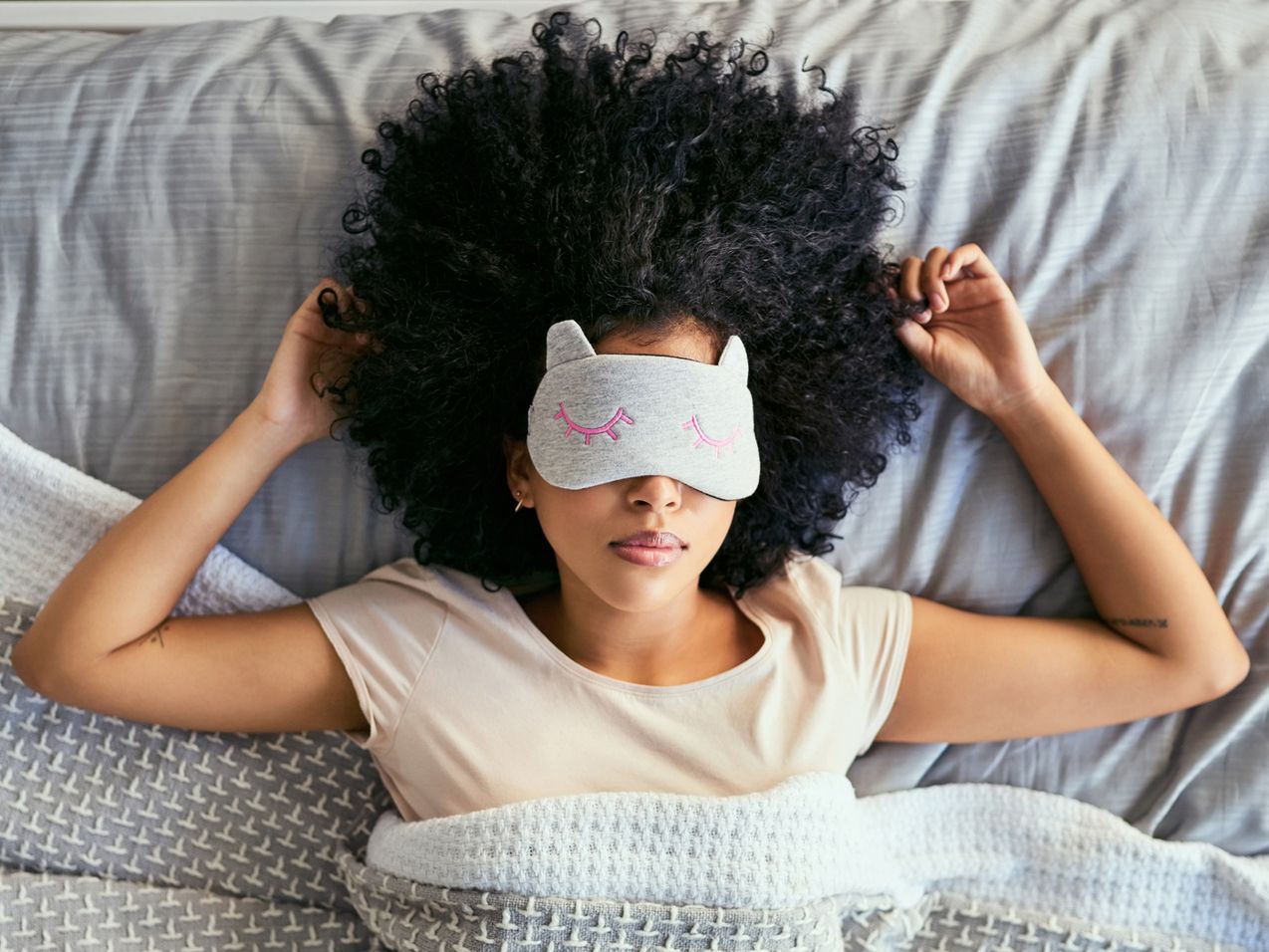 A woman with afro hair wearing a sleep mask, peacefully resting.